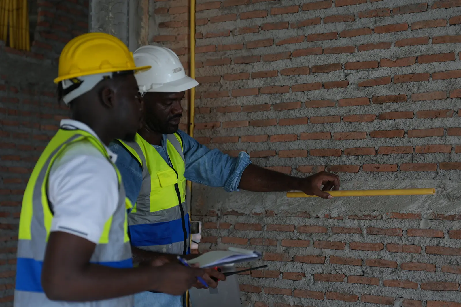 Two construction workers measuring a face-brick wall