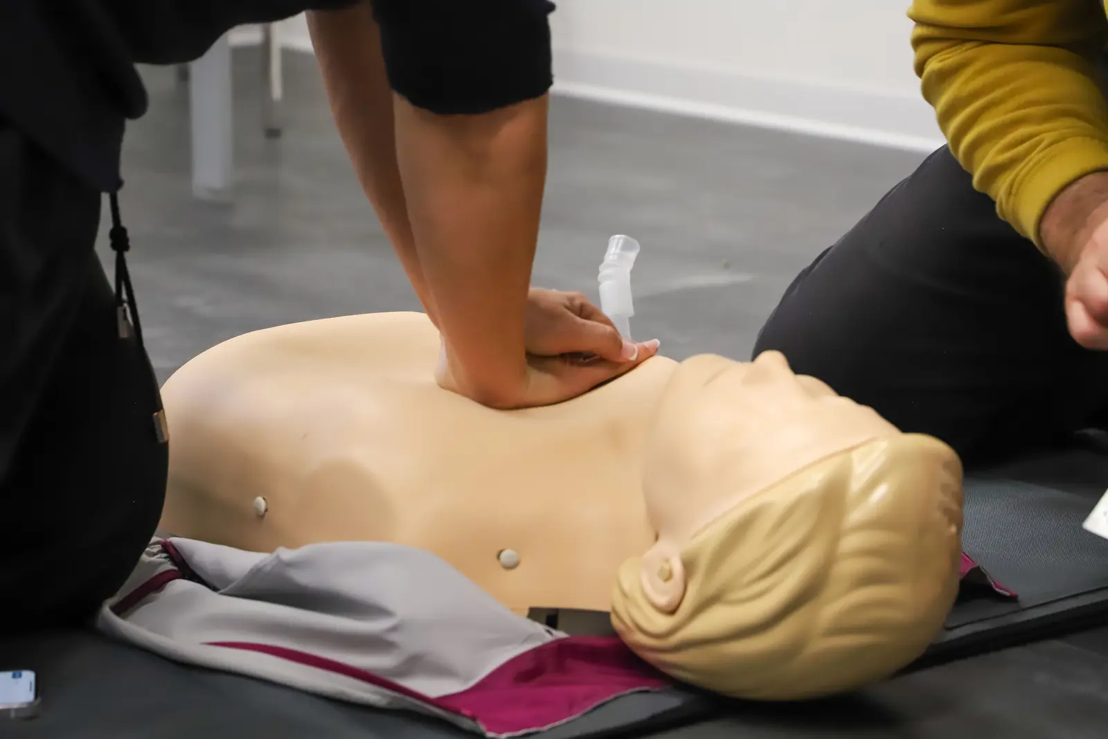 Hands performing chest compressions on a CPR training manikin