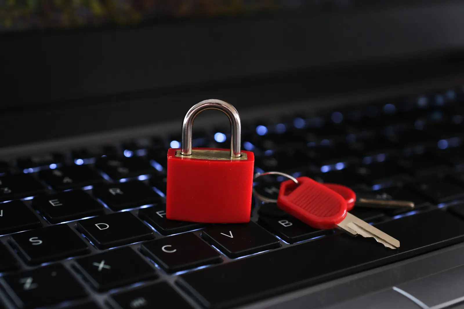 A red padlock and keys resting on a laptop keyboard